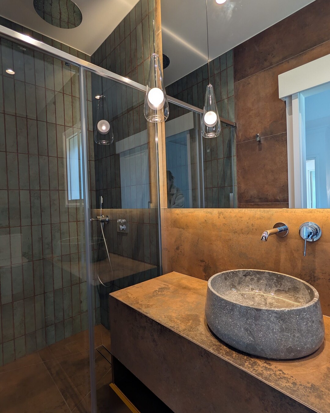 Bathroom with green tiles and a natural stone basin