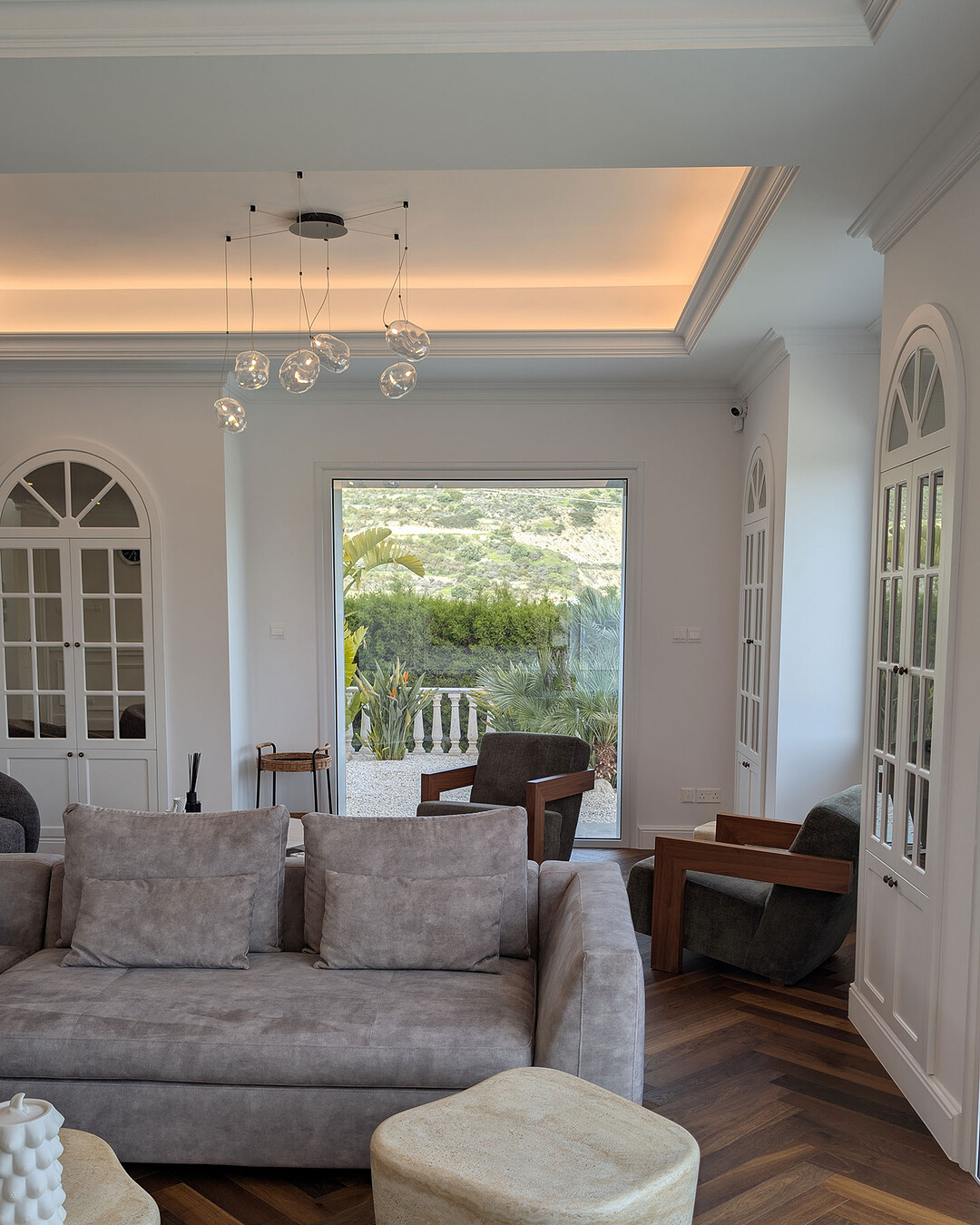 Living room with glass pendant chandelier and arched cabinets