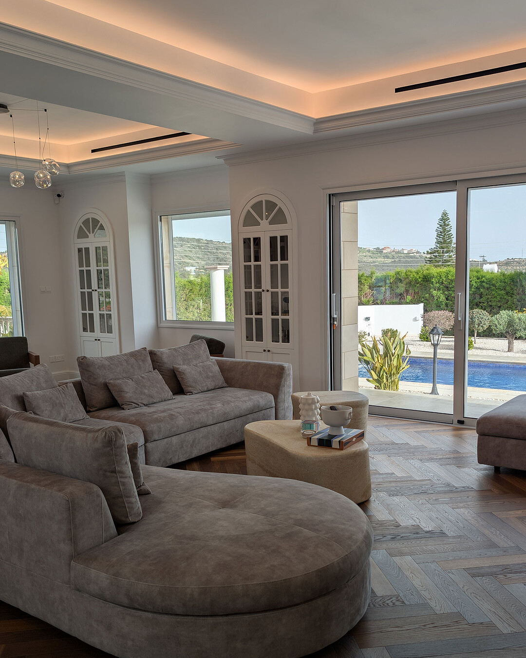 Living room with smoked oak herringbone parquet, concealed ceiling lighting and garden view